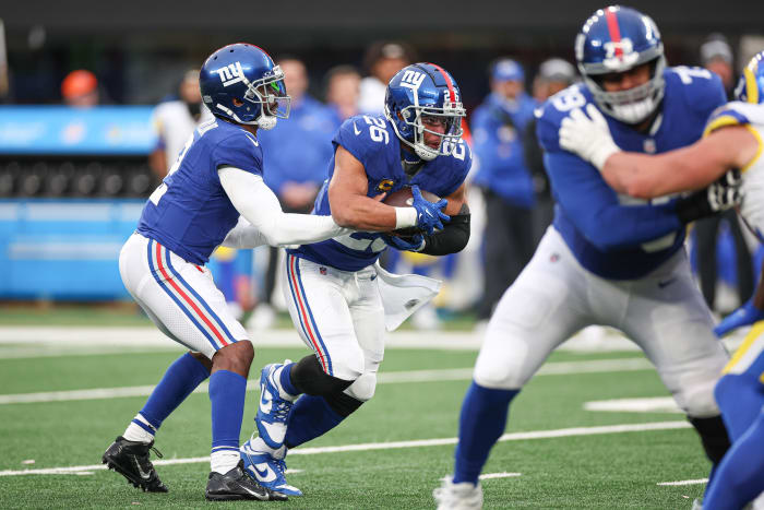 New York Giants quarterback Tyrod Taylor hands the ball off to running back Saquon Barkley.